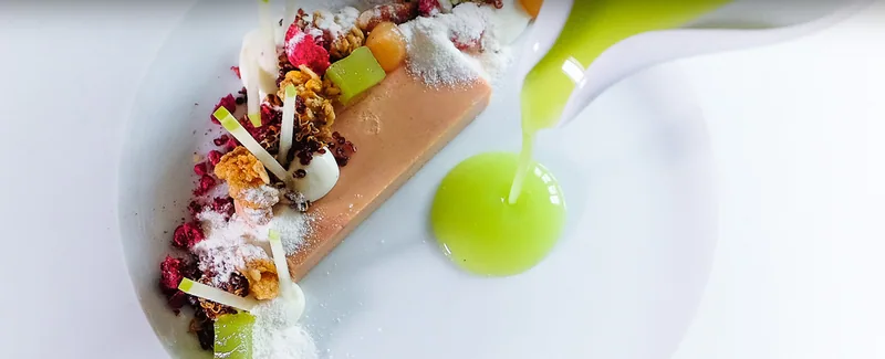 Eine Terrine mit Kräutern, grüne Sauce wird angegossen
