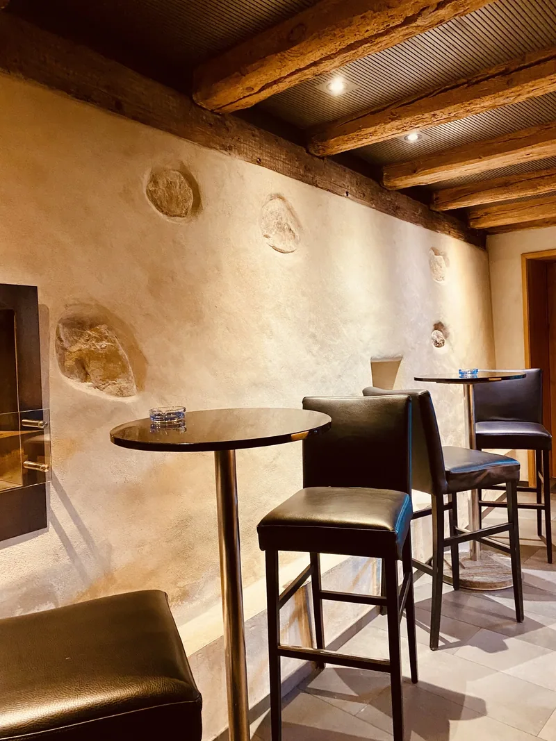 Hochtische und Barhocker an der Kalkwand der Bar