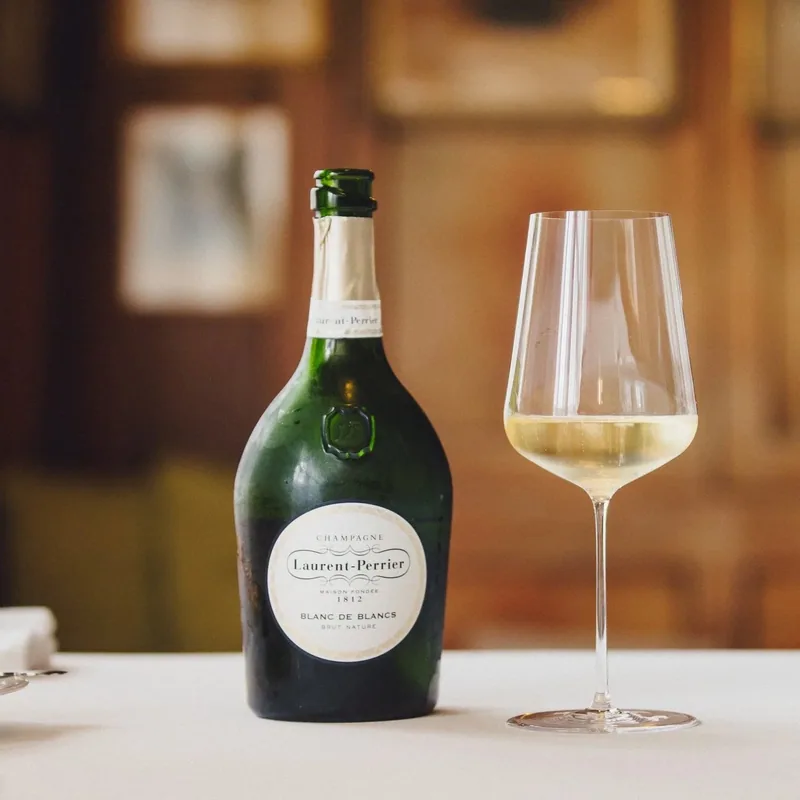 Eine Flasche Laurent-Perrier Blanc de Blancs und ein Glas auf dem gedeckten Tisch