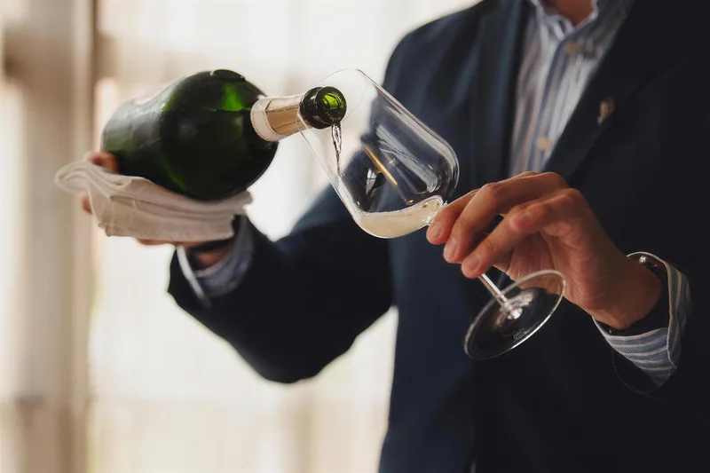 Schaumwein wird aus der Flasche ins Glas eingeschenkt