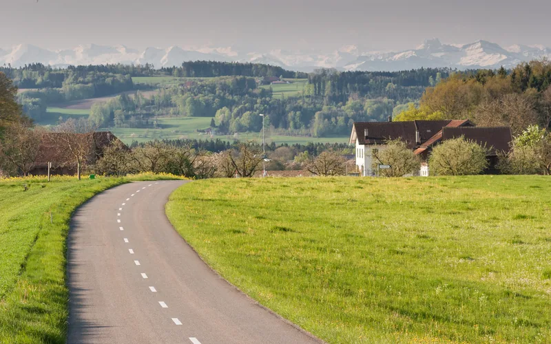Eine Landstrasse über den Seerücken bei Wäldi, dahinter die Alpen