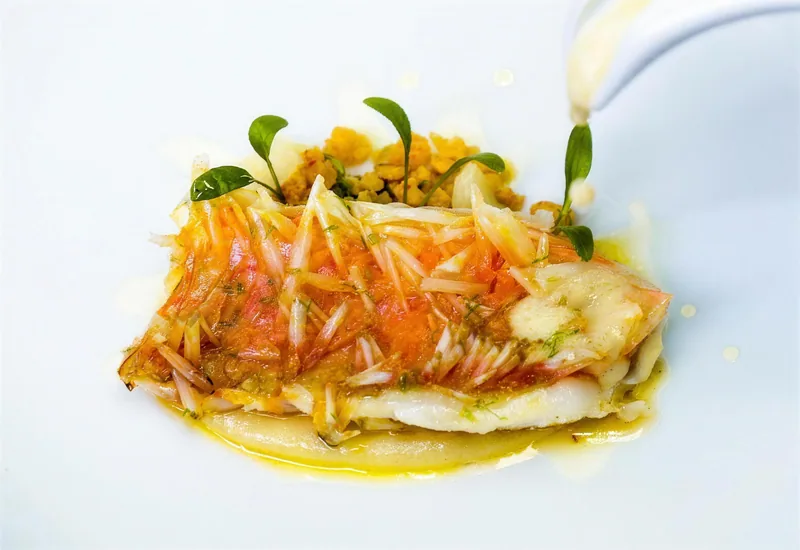Fisch mit feinen Gemüsestreifen, Sauce wird angegossen