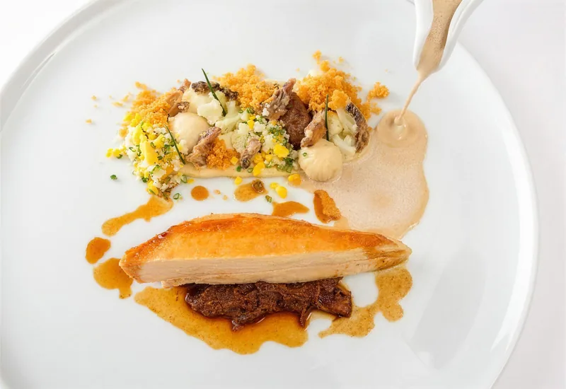 Ein Gericht mit Fisch, Pilzen und Sauce auf dem weissen Teller