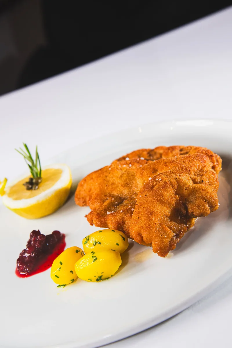 Ein paniertes Schnitzel mit Zitrone, Preiselbeeren und Kartoffeln
