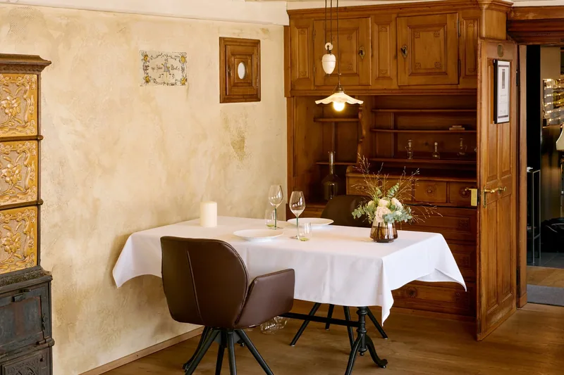 Ein gedeckter Tisch vor dem Kachelofen und dem Buffet aus Holz